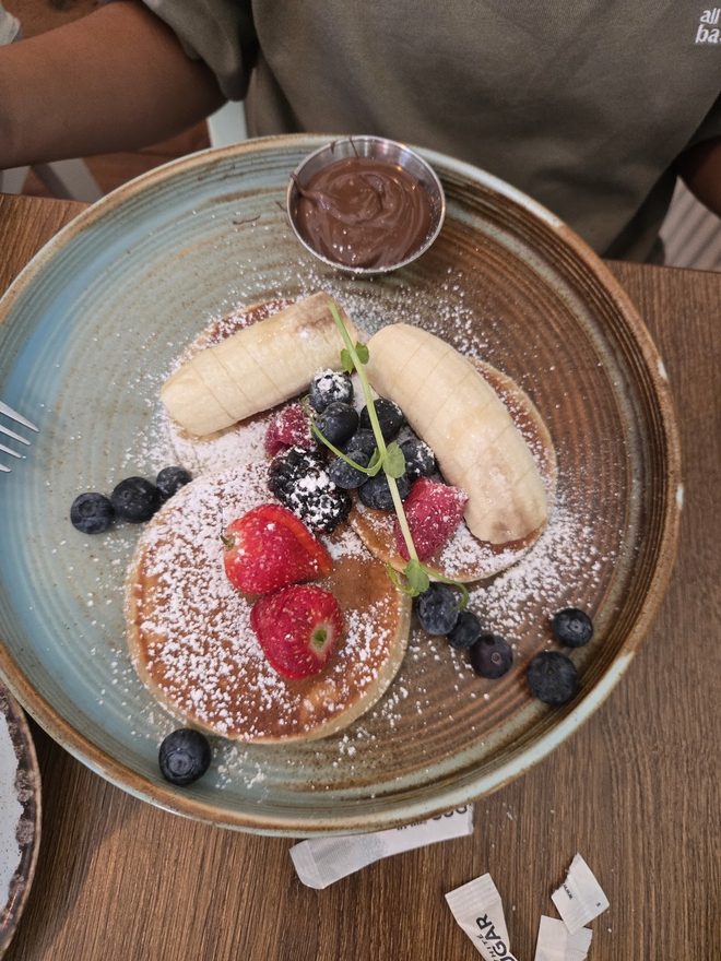 Pancakes topped with banana, raspberries, blueberries and blackberries