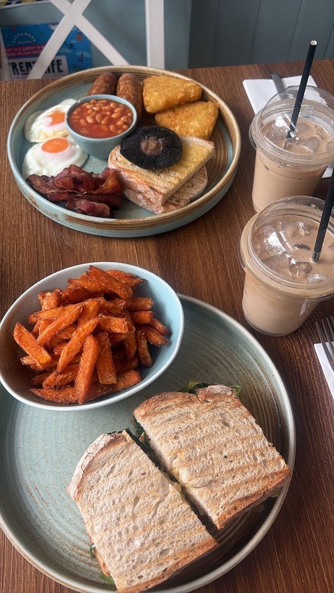 A shared table with breakfast, a toasted sandwich and two milkshakes