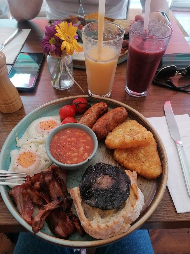 A cooked breakfast with black pudding on a busy table with juices