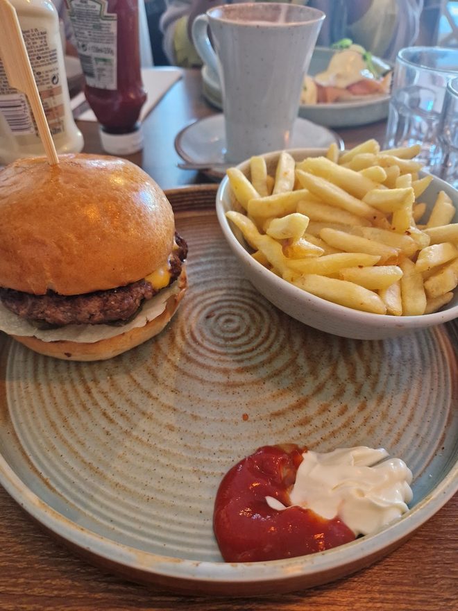 A burger in a brioche bun with fries and a dip of ketchup and mayo