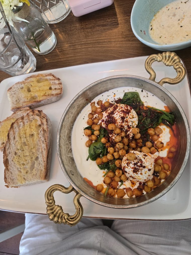 A brunch bowl of chickpeas, spinach, poached eggs and yoghurt with toast